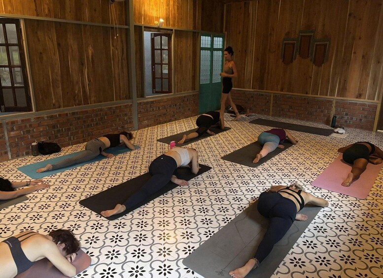 A group of people practicing yoga on mats in a room with patterned flooring and wooden walls. 5