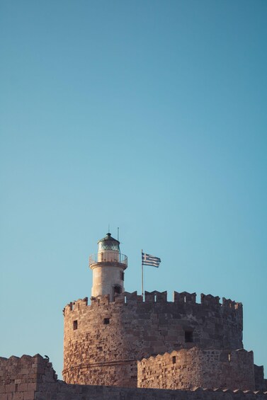 A historic stone tower with a flag, surrounded by ruins. 4