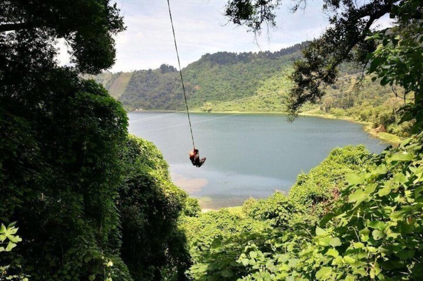 A person swinging over a lake surrounded by lush greenery. 5