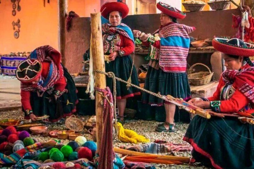Women in traditional attire with colorful textiles and accessories, engaged in a market setting with goods displayed on the ground. 3