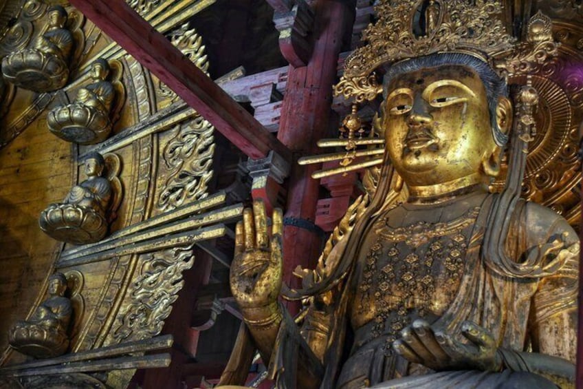 A golden statue with intricate carvings and a red pillar. 4