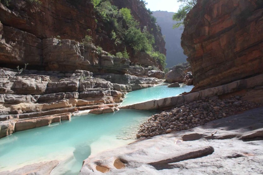 A turquoise river flowing through a rocky canyon with layered rock formations and sparse vegetation. 2