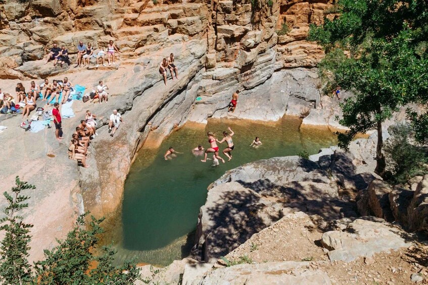 A group of people swimming in a natural pool surrounded by rocky terrain. 4