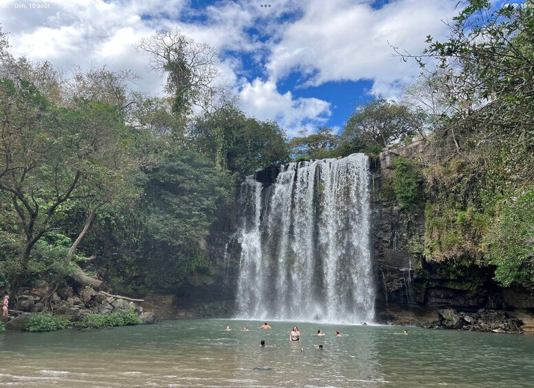 A waterfall cascading into a clear pool surrounded by lush greenery. 4