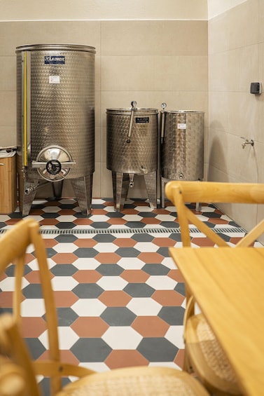 A room with hexagonal patterned floor tiles, stainless steel fermentation tanks, and wooden furniture. 2