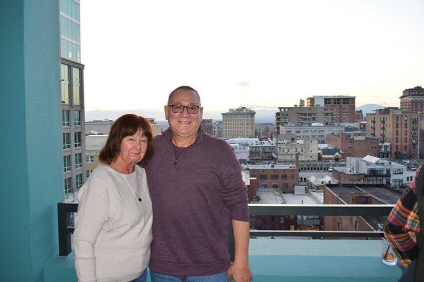 Un uomo e una donna sono in piedi su un balcone con una vista sulla città sullo sfondo. 2