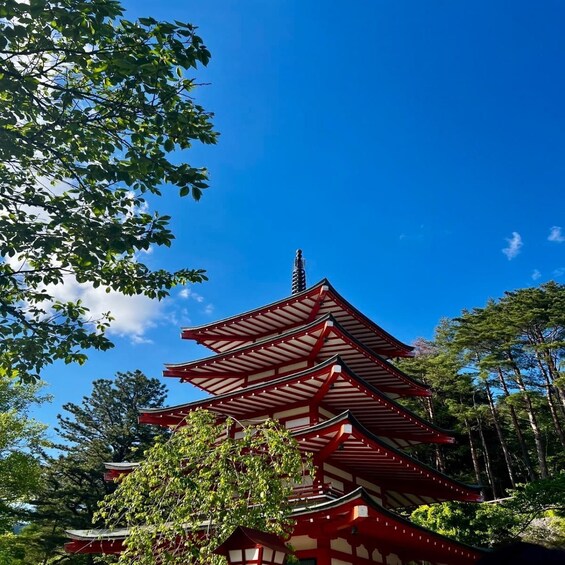 A traditional Japanese pagoda with multiple tiers, surrounded by lush greenery and a clear blue sky. 2