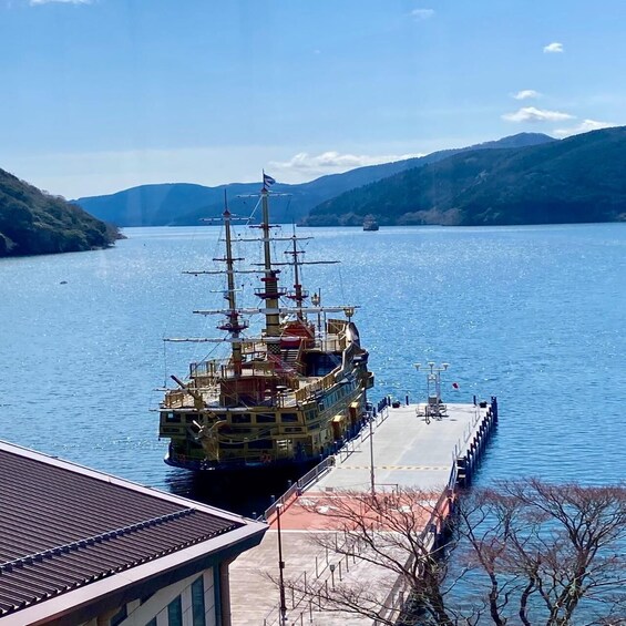 A large ship docked at a pier with mountains in the background. 4