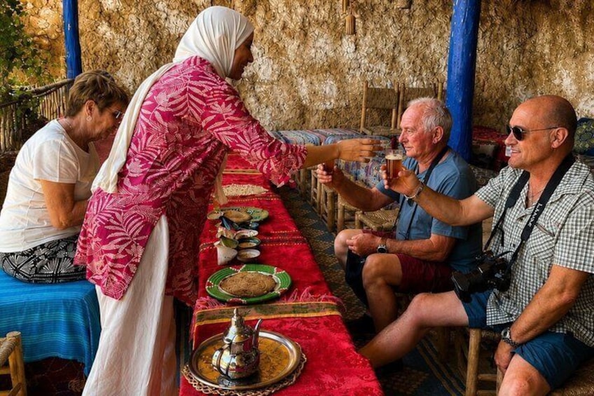 A group of people dining at a table with a red tablecloth, a traditional metal tray, and a hookah. 2