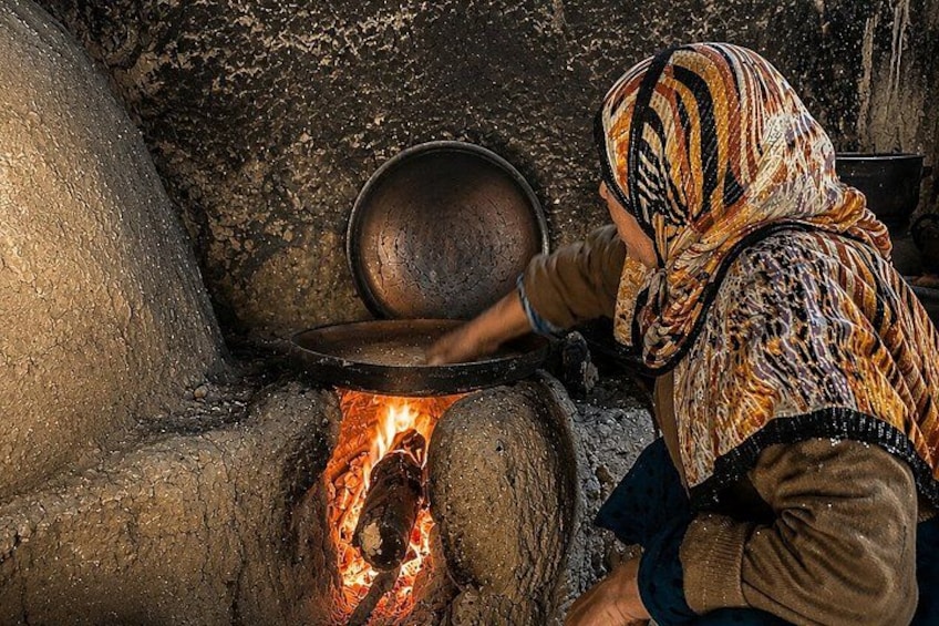 A person cooking over an open fire in a traditional oven. 1