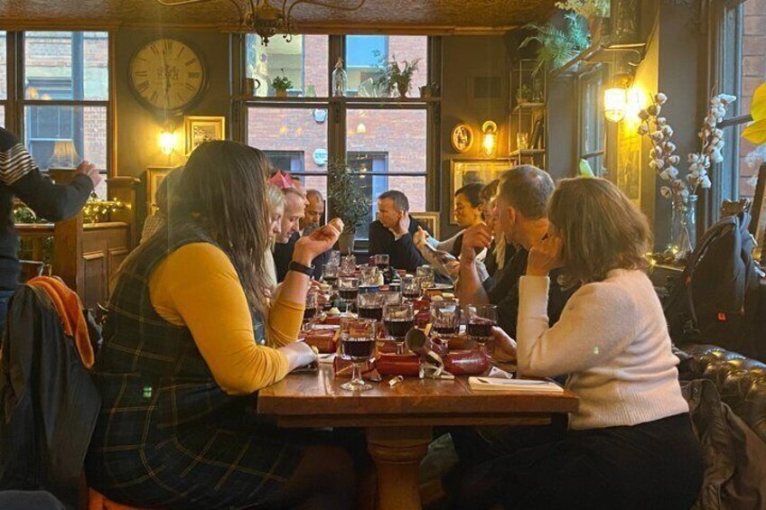 A group of people dining at a restaurant with a brick wall and large windows in the background. 4