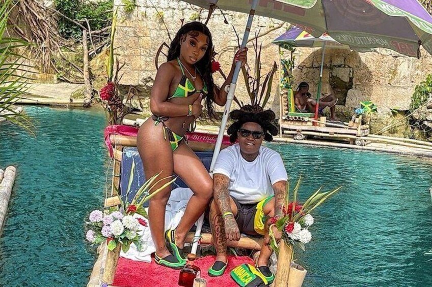 A person in a white shirt and green shorts sitting on a boat in a pool with a woman in a green bikini. 1