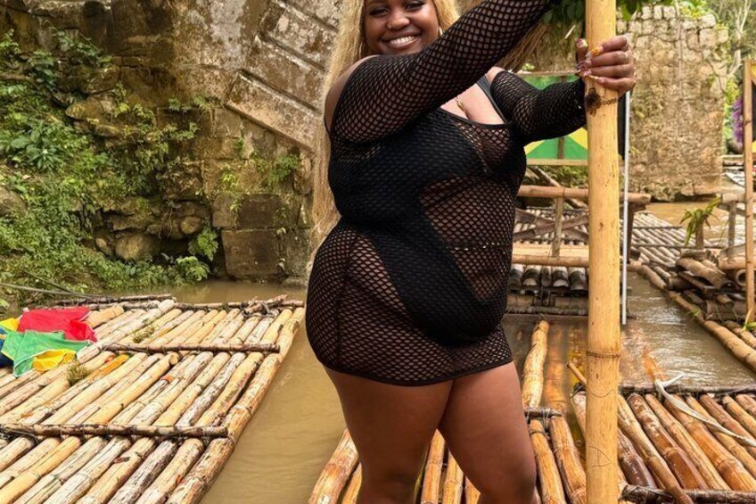 A person standing on a bamboo raft in a river. 5