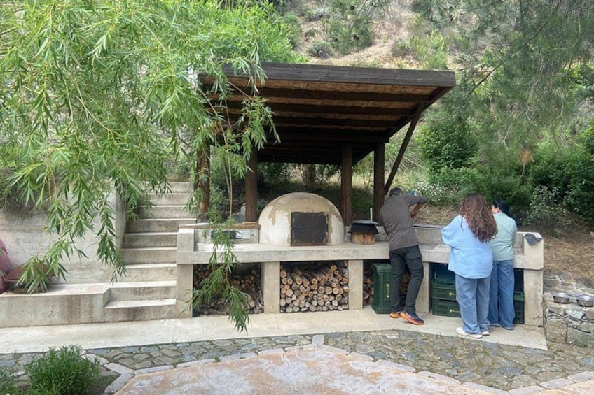 An outdoor pizza oven with people cooking. 3
