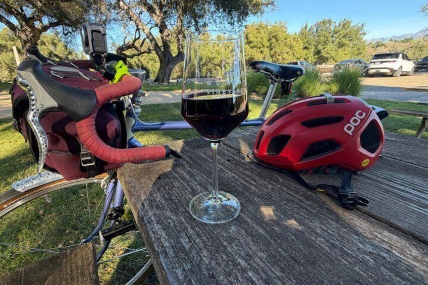 A bicycle with a red helmet and a glass of red wine on a wooden table. 4