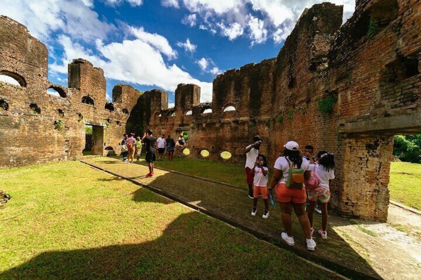 A group of people walking through a historical site with brick ruins and arches. 1