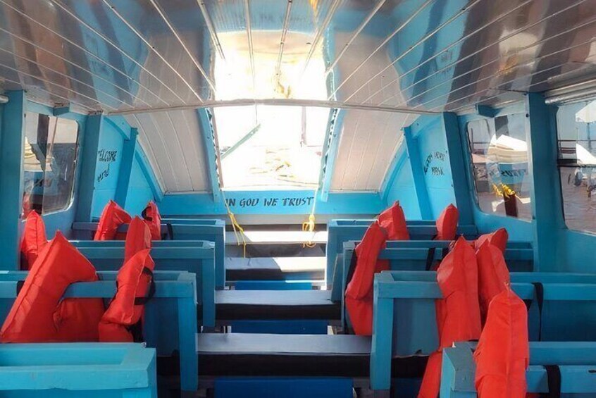 A blue boat interior with rows of seats and a sign reading 'IN GOD WE TRUST'. 4