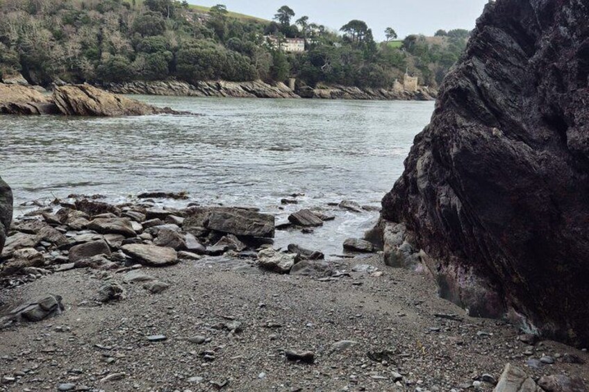 A rocky shoreline with a large rock formation and a river. 5