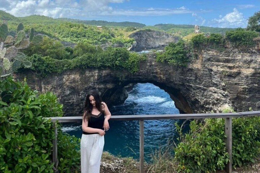 A person standing by a railing overlooking a natural rock formation with a water channel. 4