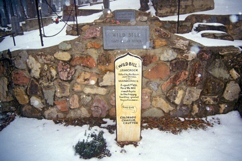 A stone wall with a plaque and a wooden sign with text. 3