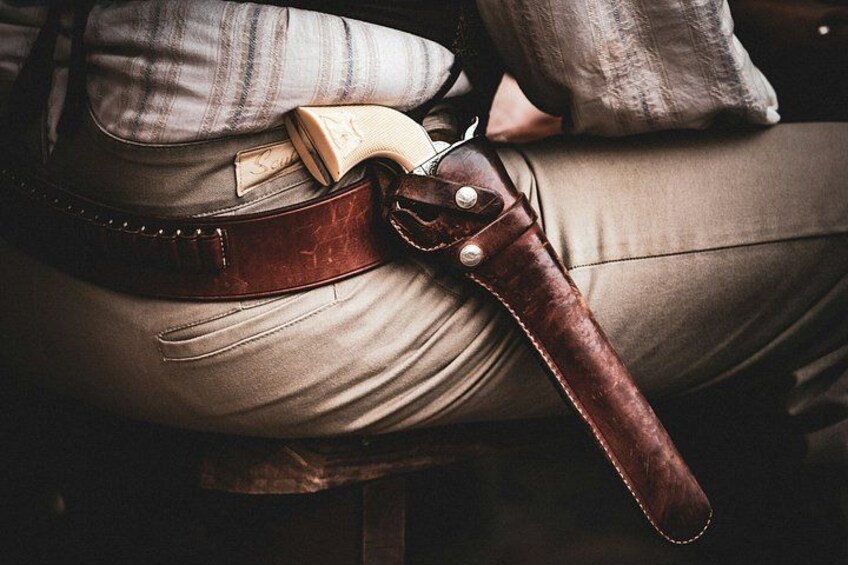 A leather belt with a buckle and a folded piece of paper on a person's lap. 4