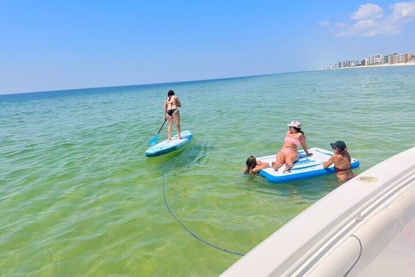A person paddleboarding in clear water with a cityscape in the background. 5