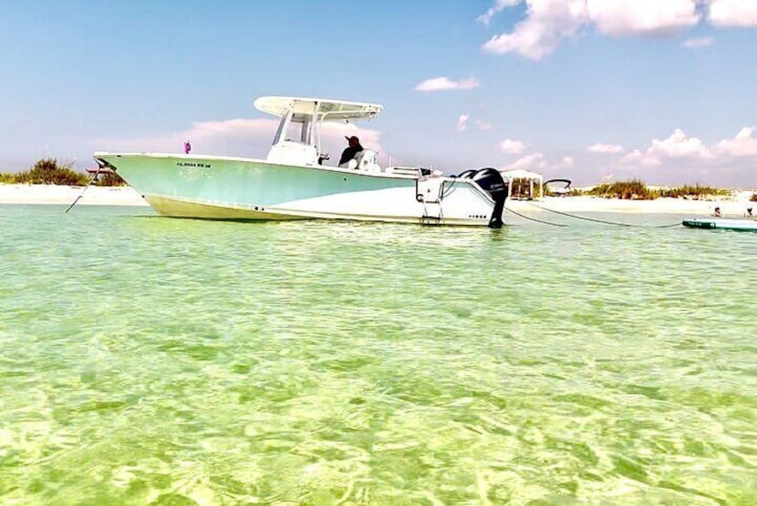 A boat anchored near a sandy beach with clear water. 3