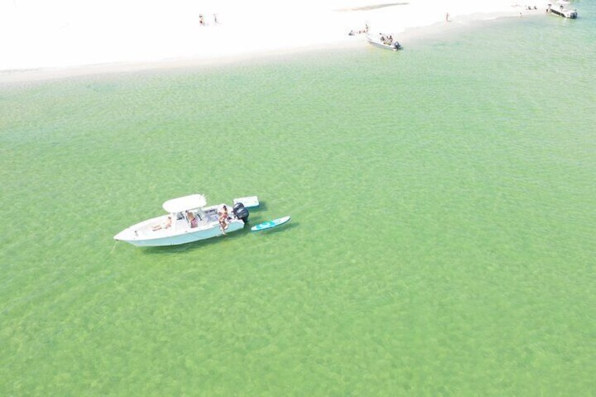 A speedboat on a calm, greenish water body with a sandy beach in the background. 1