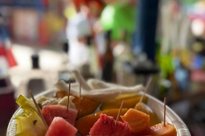 A basket of sliced fruits with toothpicks. 3