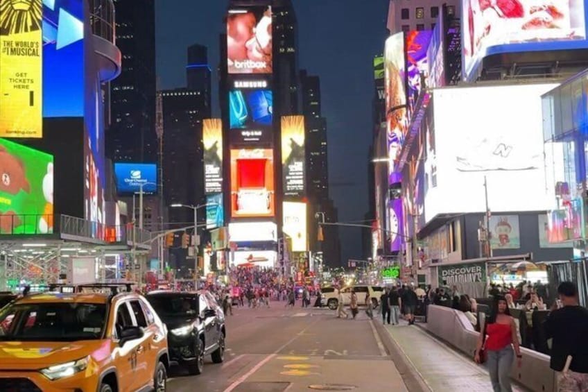 A busy urban street at night with illuminated billboards and vehicles. 5