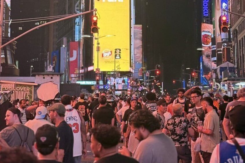 A busy urban street at night with illuminated billboards and a crowd of people. 3