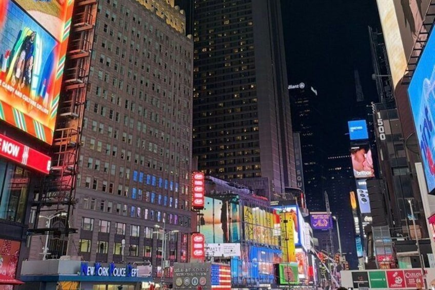 A brightly lit urban street at night with illuminated billboards and skyscrapers. 2