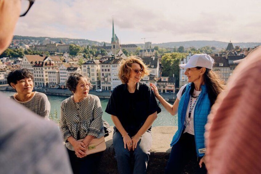 A group of people standing by a waterfront with a cityscape in the background. 1