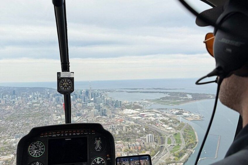 A helicopter cockpit with a cityscape view, including a river and a tall building. 2
