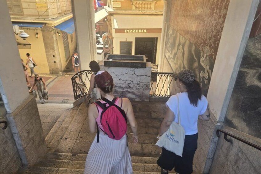 People descending a stone staircase in a narrow alleyway with a pizzeria in the background. 3