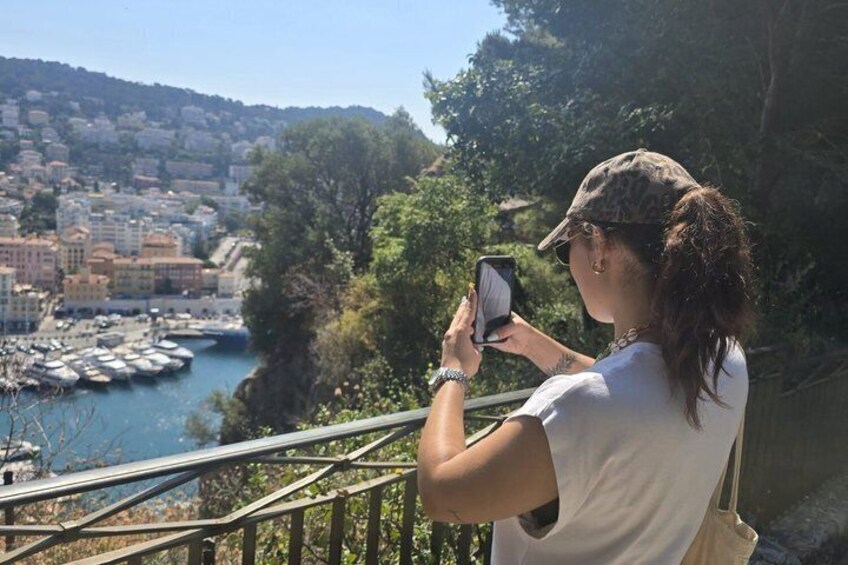 A person taking a photo with a smartphone overlooking a coastal town and a body of water. 4