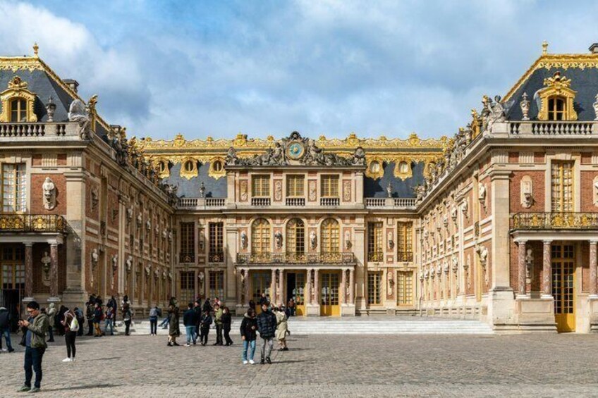 A historic building with ornate architecture, a courtyard, and people walking around. 3