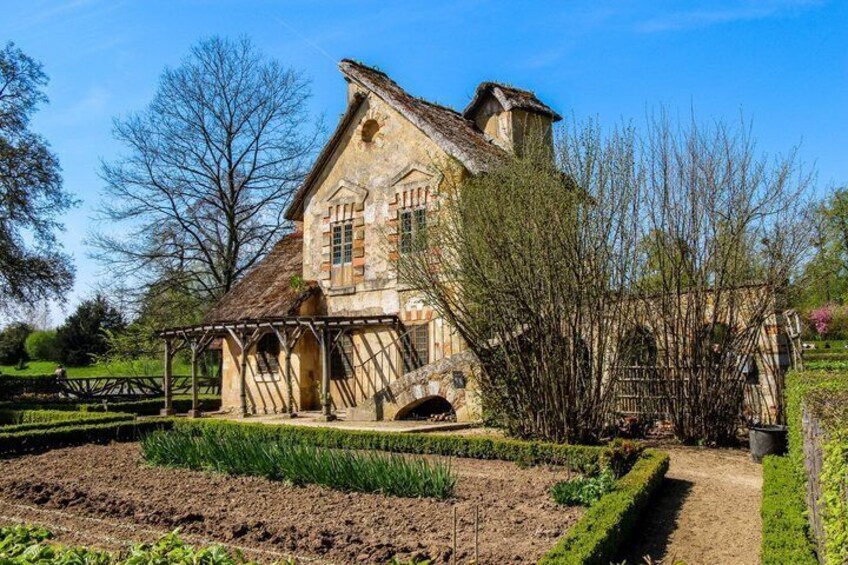 A stone house with a thatched roof, surrounded by a well-maintained garden and a wooden fence. 5