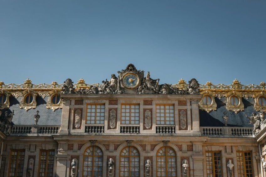 A grand building with ornate sculptures, large windows, and a clock. 1
