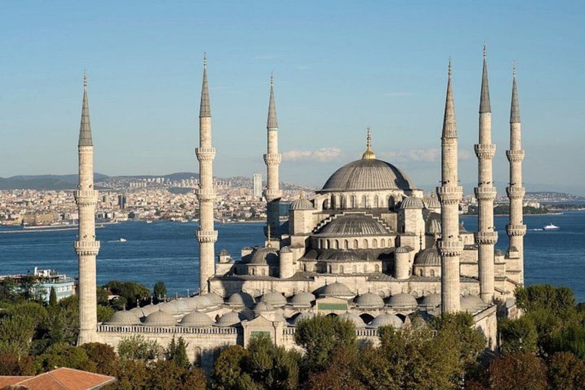 A historic mosque with multiple minarets and domes, surrounded by a cityscape and a body of water. 4
