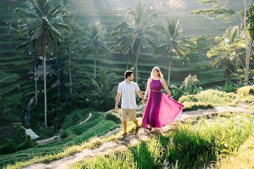 A couple walking on a terraced field with palm trees in the background. 3