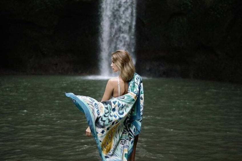 A person standing in water with a waterfall in the background. 5
