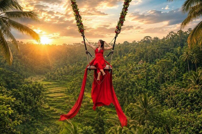 A woman in a red dress on a swing with a lush green landscape and palm trees in the background. 4