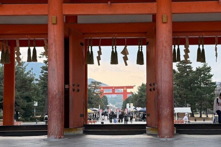 A traditional Japanese torii gate with a red backdrop and a view of a mountain in the distance. 3