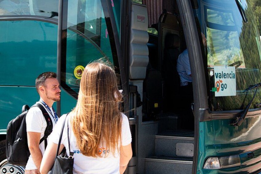 A bus with a 'valencia go' sign, a person with a backpack, and another person standing by the bus door. 2