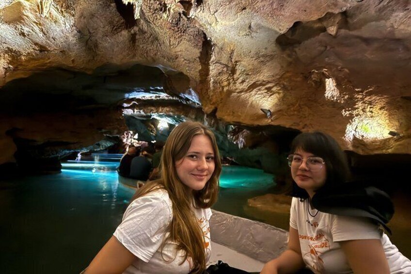 Two people inside a cave with water features and stalactites. 1
