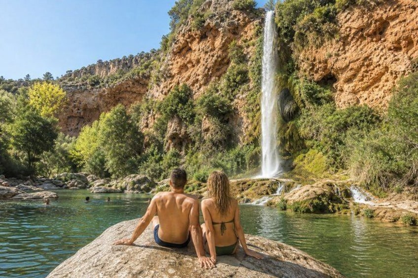 Two people sitting on a rock by a waterfall. 5