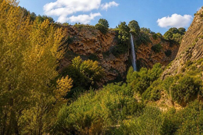 A waterfall cascading down a rocky cliff surrounded by dense green foliage. 3
