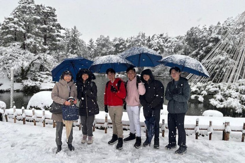 A group of people standing in a snowy landscape with a river and snow-covered trees in the background. 2