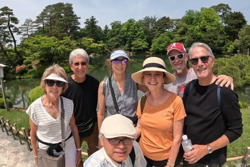 A group of people standing by a lake with trees in the background. 5